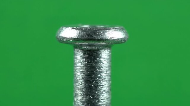 Industrial countersunk rivet rotating slowly against a chroma key green screen for mechanical engineering and construction visual effects