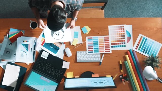 Top view of smart businessman hand choosing color palettes while designing logo graphic. Aerial view of professional interior designer design and select color theme by using color palettes. Symposium.