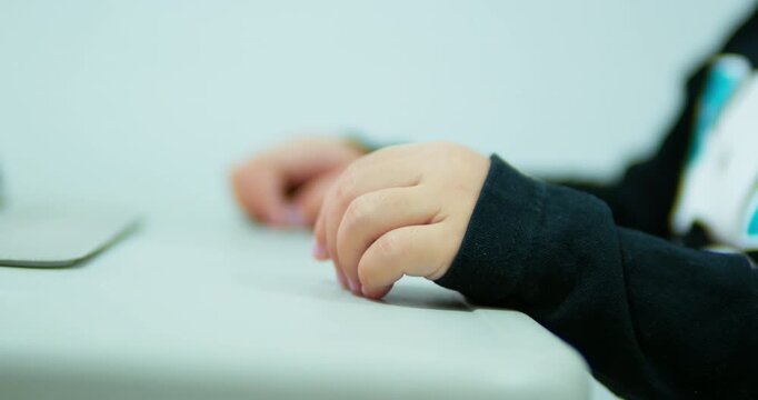 A young two-year-old girl sits comfortably at home, looking at a digital tablet. She is actively engaged in watching an educational video, showcasing modern childhood and technology.