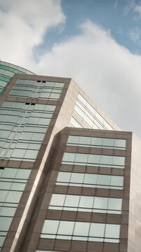 Time-lapse of a modern glass skyscraper corporate building under bright afternoon sky, concept of business success.