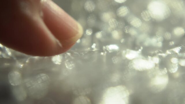 Macro Close Up View of Thumb Popping Plastic Bubble Wrap Packaging