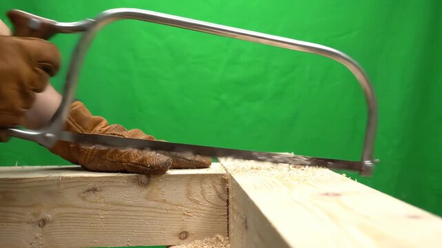 Traditional steel bow saw tool moving in a back and forth cutting motion isolated on a bright chroma key green screen background
