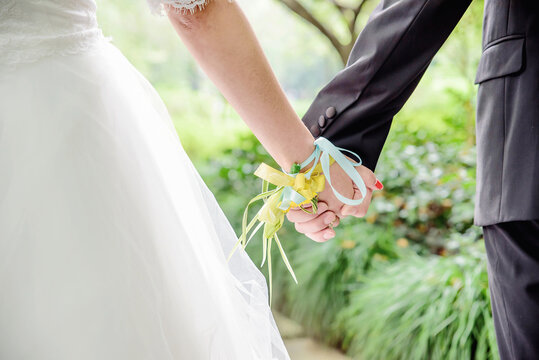 Close-up of a couple holding hands at an outdoor forest wedding