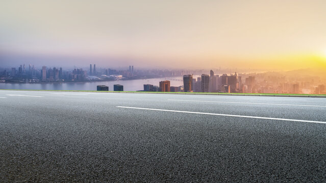 Empty Asphalt Road Overlooking City Skyline at Sunrise