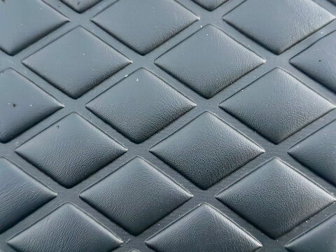 Black rubber floor mat texture. Diamond pattern non-slip industrial surface background.