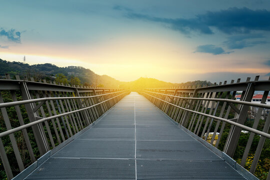 Metal Pedestrian Bridge Leading to the Sunrise Over Hills