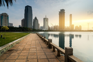 Obraz premium City Skyline Reflected in Calm Lake at Sunrise