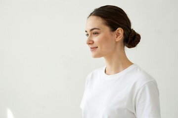 Fototapeta premium Young woman in white t-shirt looking away. Portrait of a smiling girl on plain background.