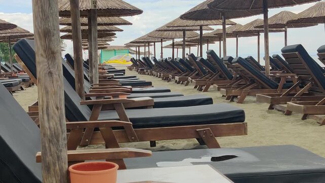Rows of empty beach loungers and parasols create orderly resort seating on sandy shore