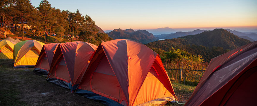 Banner Tent Camping trip outdoor hiking mountain hill. Tent camp in nature background sunrise top mountain. Adventure Travel with copy space. Banner Picnic tent green nature campground forest
