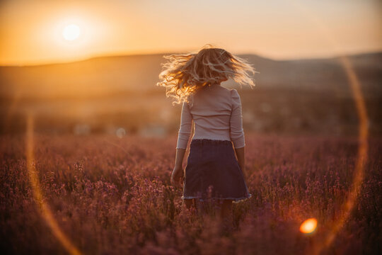 Child lavender field sunset girl spinning in flowering meadow back lit by golden sun