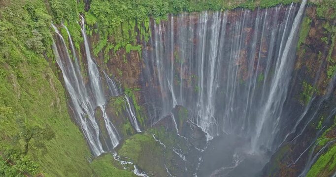 Scenic aerial photography of Indonesia's stunning Tumpak Sewu Waterfall, a world-class travel destination surrounded by lush greenery, volcanic terrain, and dramatic waterfalls.