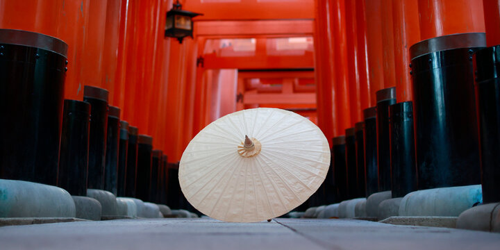 Traditional Japanese Paper Umbrella on Ground Inside Red Torii Gate Tunnel at Fushimi Inari Kyoto