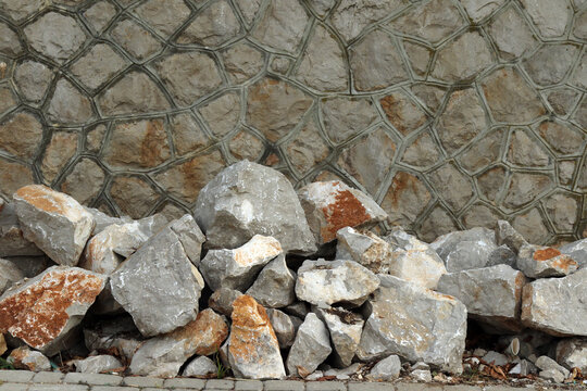 Pile of Large Rough Stones Against a Retaining Stone Wall Background