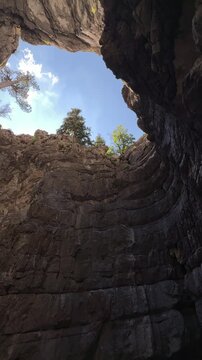 Vertical panorama of a colossal cavern floor looking up through jagged holes to the open sky