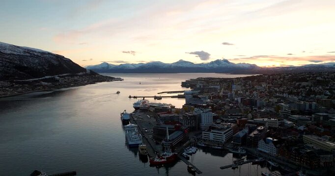 Tromso harbor and strait in early winter with cityscape view, sunset aerial