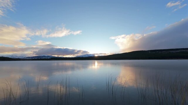 Stunning aerial footage soars over Laguna La Zeta at sunset in Esquel, Patagonia. Calm waters mirror vivid skies with golden hues, dramatic clouds, creating a breathtaking mood.