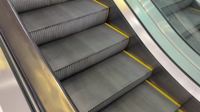 Escalator steps moving, automatic stairs ascending in a modern public building. High angle static shot.