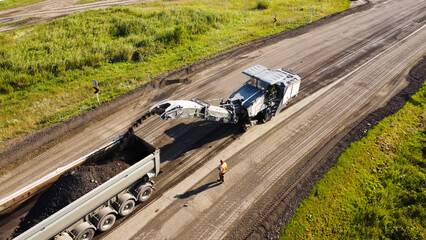 Aerial Shot of Cold Recycler Loading Milled Asphalt into Dump Truck © Andrey