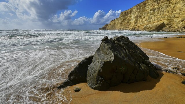Red Beach, dream beach in the neighboring bay of Matala, large rock on sandy beach with waves and blue and white sky in the background, Matala, south coast, Crete, Greek Islands, Greece