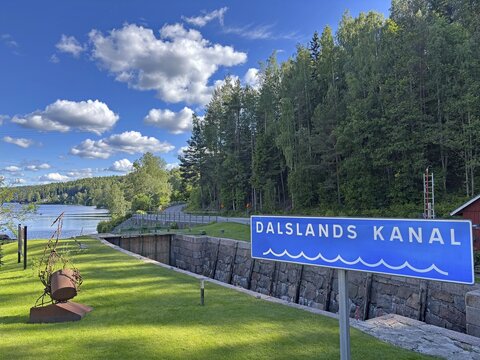 Dalslands canal sign against wooded background and river. Clear sky with few clouds, Dals-Rostock, Dalsland Canal, Dalsland, Mellerud Municipality, Sweden