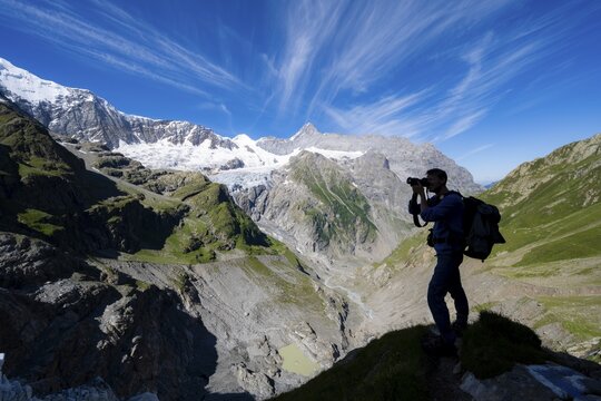 Silhouette of photographer with camera in front of mountain panorama, picturesque high alpine mountain landscape with Grindelwald-Fiescherfirn glacier, hiking to Schreckhornh&uuml;tte, Bernese Oberland, Switzerland