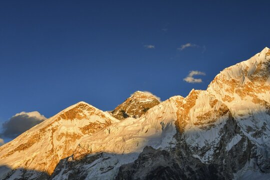 Everest base camp trek. Mountain peak. Mount Everest, Lho La, Nuptse, Lhotse peaks. Sagarmatha National Park, Nepal. Golden sunset with clear blue sky and Mt Everest peak view