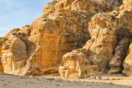 Hiking group on Back Door Trail from Little Petra to Petra walking through sandstone desert valley Jordan adventure tourism.Popular hiking moderate easy route