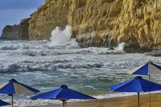 Red Beach, a dream beach in the neighboring bay of Matala, beach with blue umbrellas against rocky coast and rising waves, Matala, south coast, Crete, Greek Islands, Greece