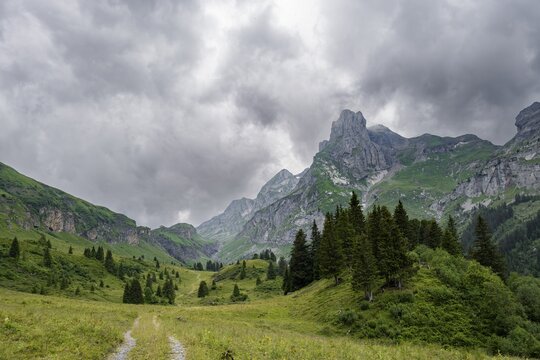 Hiking trail in a valley, rocky peak Spaltenhorn, mountain landscape with dark clouds, Bernese Alps, Bernese Oberland, Switzerland