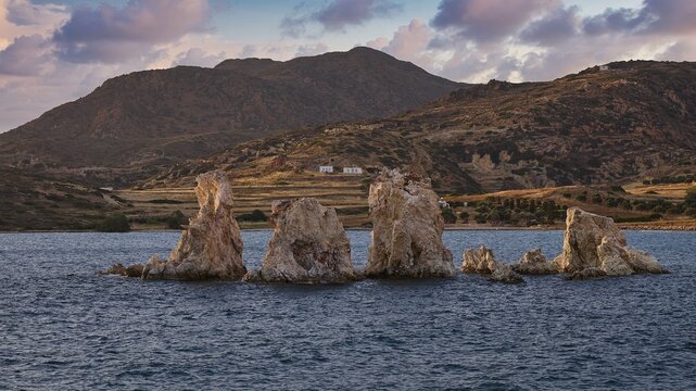 Rocks and blue waters with mountains in the background and clouds, Aspragremna, White Cliffs, Mavorspilia Beach, Kimolos Island, Kimolos, Cyclades, Greek Islands, Greece