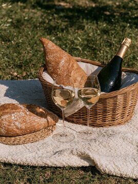 Outdoor picnic with sparkling wine, bread and two glasses on blanket