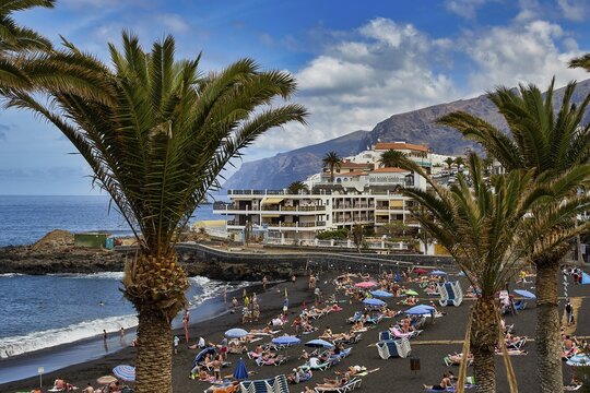 Puerto de Santiago, popular black sandy beach with many sun worshippers and palm trees by the sea in front of a coastal town, Masca, Barranco de Masca, canyon, Teno, Teno Mountains, northwestern Tenerife, Tenerife, Canary Islands, Spain