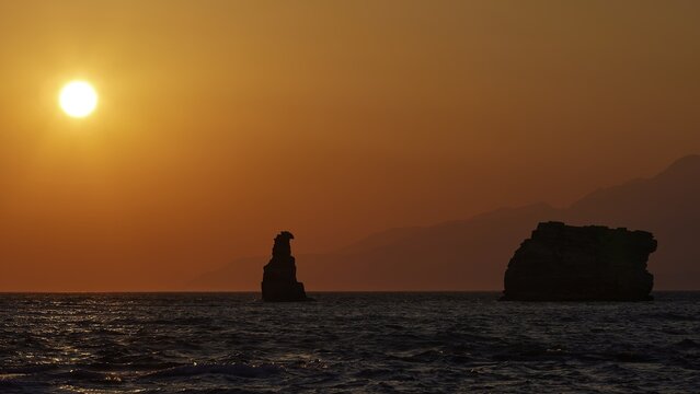 Calm sunset over the sea with a distinctive rock and mountains in the distance, sunset, south of the Amari Basin, Central Crete, Triopetra, rocks in the sea, Crete, Greek Islands, Greece