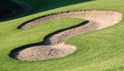 Obraz premium Golf bunker shaped like a question mark. Sand trap on green grass representing uncertainty.