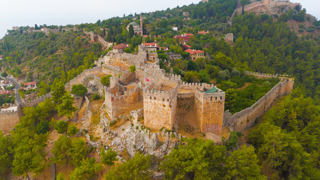 Alanya, Turkey. Ehmedek Castle, massive stone fortification with three defensive towers and cisterns, aerial drone view over forested mountain terrain