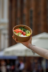 A young woman is holding a poke bowl in a delivery box. © Cavan