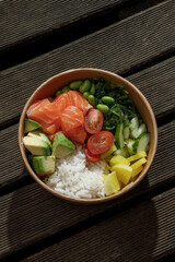 Salmon poke bowl in a delivery box on a wooden surface. Isolated © Cavan
