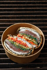Sushi burger on a metal wire rack. Delivery box. Art photo © Cavan