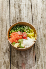 Salmon poke bowl in a delivery box on a wooden surface. Isolated © Cavan