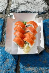 Philadelphia salmon sushi roll on road markings. Delivery box. © Cavan