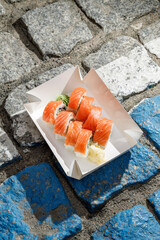 Philadelphia salmon sushi roll on road markings. Delivery box © Cavan