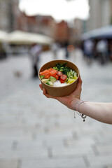 A young woman is holding a poke bowl in a delivery box. © Cavan