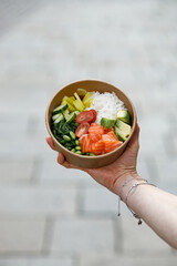 A young woman is holding a poke bowl in a delivery box. © Cavan