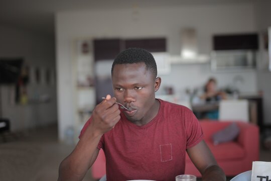 Young Black man eating a meal at home