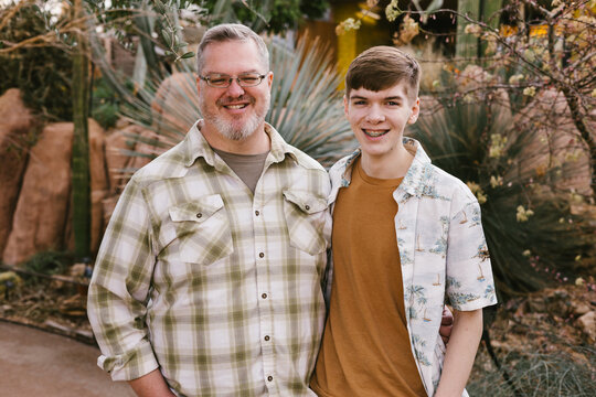 Happy father and teenage son smiling in a garden