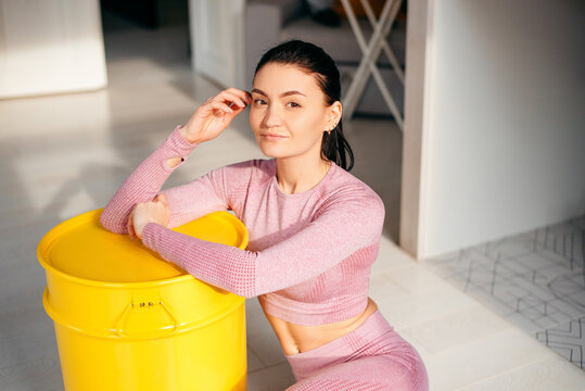 Woman in sport clothes sitting near barrel at home
