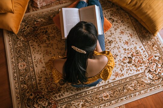 Overhead view of woman reading a book at home