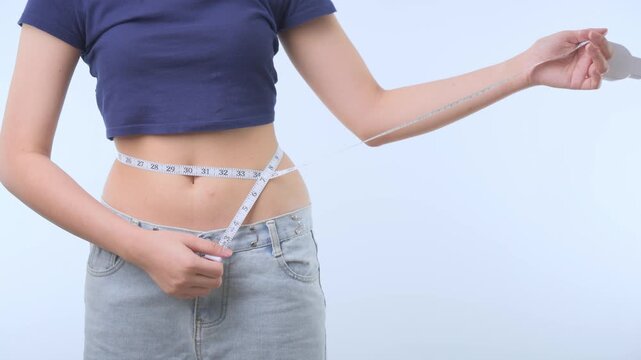 Proud fit woman uses measure tape around slim waist showing healthy diet body progress during successful weight loss journey with happy smile