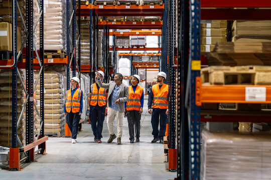 Diverse group of logistics workers and a manager inspecting inventory and discussing operations in a large distribution warehouse